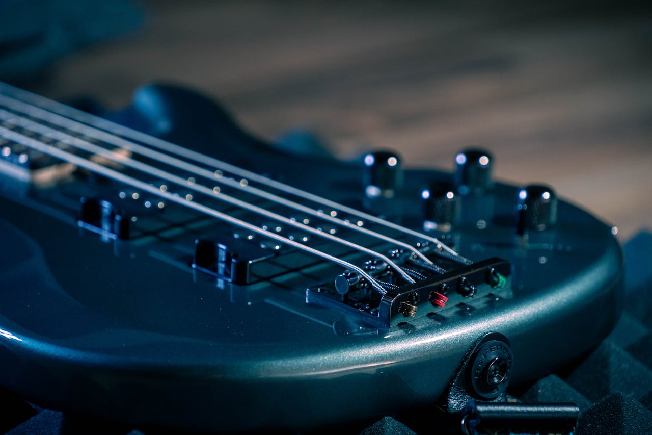 Detailed view of strings and pickups on a dark blue bass guitar with shallow focus.